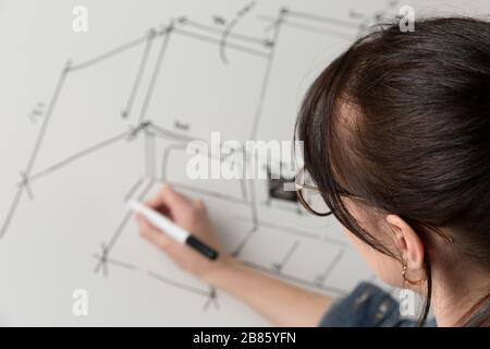 Gros plan d'un jeune architecte féminin dessinant un croquis pour un nouveau projet maison célèbre. Concept de travail sur les dessins techniques Banque D'Images