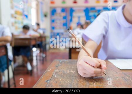 Testez le potentiel des étudiants en suivant le concept des examens, les enfants sont très déterminés, les examens sont placés sur la table, main tenant un crayon Banque D'Images