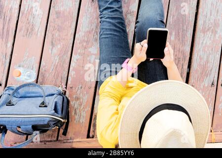 Jeune femme assise sur le parquet avec téléphone mobile. Femme asiatique touriste routard souriant et utilisant smartphone voyager seuls vacances outdo Banque D'Images