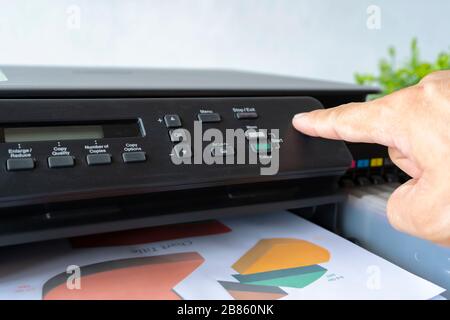 Doigts qui pressent le bouton, l'imprimante est entièrement fonctionnelle, située sur le bureau. Il est important au bureau de présenter le travail et le succès Banque D'Images