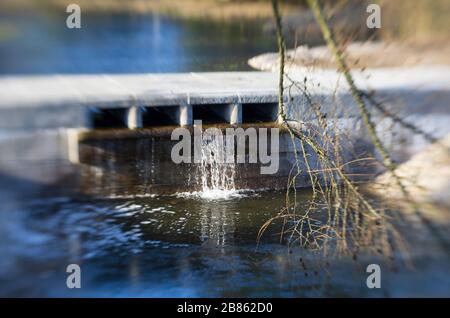 Paysage printanier avec un pont et une petite chute d'eau encadrée par des branches closeup Banque D'Images