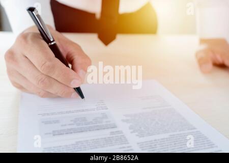 Les hommes d'affaires signent des contrats. Porter un maillot blanc Noir noir, cravate noire, look digne, accord commercial complet avec les signatures. Banque D'Images