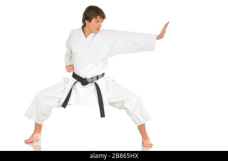 Un jeune homme de talent professionnel en karaté dans un costume kimono avec ceinture noire montre une position de combat posant sur un fond blanc. Espace publicitaire Banque D'Images