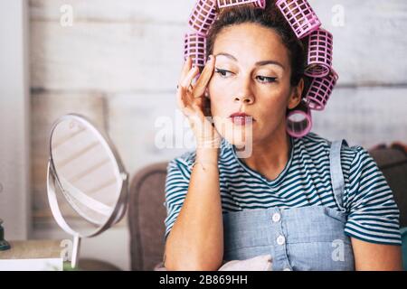 Femme adulte d'âge moyen à la maison avec un miroir de vérification des wrinlkes penser à la chirurgie cosmétique - les gens et les soins de beauté - le concept de vieillissement et la peau healt Banque D'Images