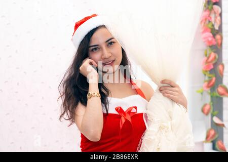 Une belle femme asiatique vêtue de rouge et portant un chapeau de Père Noël est debout et souriante à Noël. Et agir de différentes façons. Banque D'Images