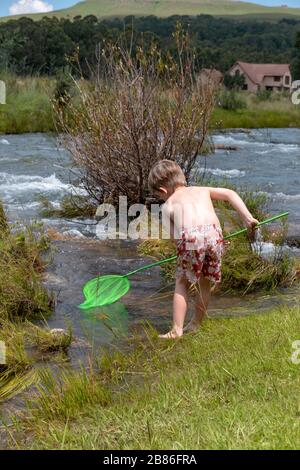 vue rapprochée d'un jeune enfant qui joue dans l'eau avec un poteau de pêche Banque D'Images