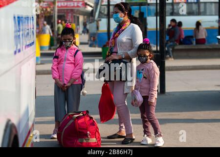 Une femme avec ses enfants portant des masques de protection attend d'embarquer dans un bus longue distance au milieu des menaces de Coronavirus.le gouvernement népalais a décidé de fermer les lieux publics tels que les écoles, les salles de cinéma, les clubs de nuit, les clubs de santé, les centres culturels et la zone sportive, Du 19 mars au 30 avril 2020 dans le cadre de mesures de précaution contre la propagation du virus corona Covid-19. Banque D'Images