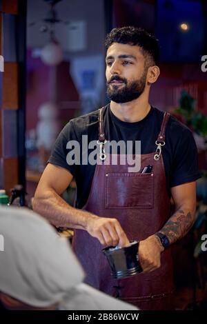 Portret Jeune coiffeur à son coiffeur. Travailler dans le salon de coiffure, le processus du salon de coiffure. Banque D'Images