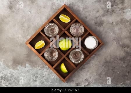 Tequila projectiles, limes et sel sur planche en bois sur fond gris Banque D'Images