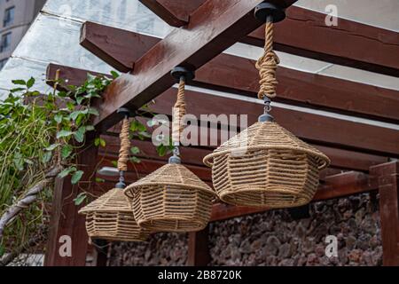 Suspension traditionnelle chinoise tissée suspendue depuis le toit en bois. Lampes à ficelle en osier fabriquées à la main dans un style écologique. Éclairage extérieur asiatique Banque D'Images