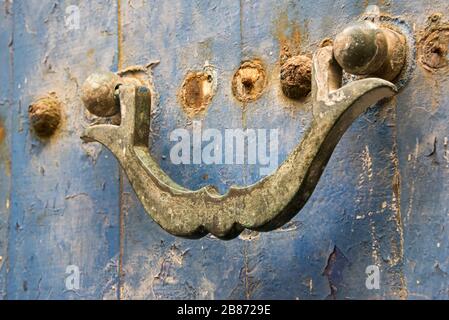Essouria, Maroc - septembre 2017: Un knocker de porte rouillé sur la porte avec de la peinture bleue pâle Banque D'Images