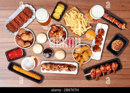 Composition d'en-cas frits Fast food, saucisses, frites et bière sur table en bois Banque D'Images