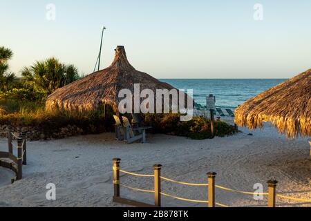 Lido Beach, Floride, États-Unis - 20 mars 2020. Les huttes de palmier sont baignées de lumière tôt le matin lorsque le soleil se lève sur le golfe du Mexique. Banque D'Images