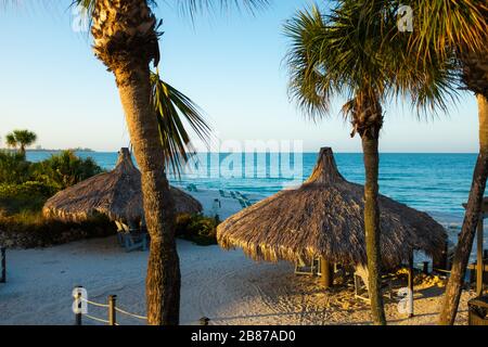 Lido Beach, Floride, États-Unis - 20 mars 2020. Les huttes de palmier sont baignées de lumière tôt le matin lorsque le soleil se lève sur le golfe du Mexique. Banque D'Images