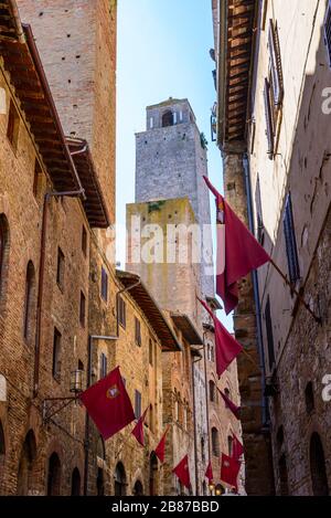 Torre Rognosa, Torre Pettini, et via S. Matteo avec des drapeaux rouges sur les murs dans le centre historique de San Gimignano, province de Sienne, Italie. Banque D'Images