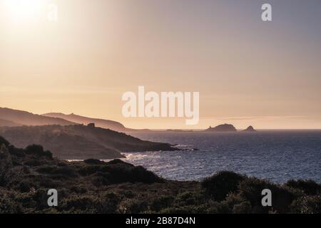 Soleil de soirée sur la côte accidentée de la Corse avec Ile Rousse au loin Banque D'Images