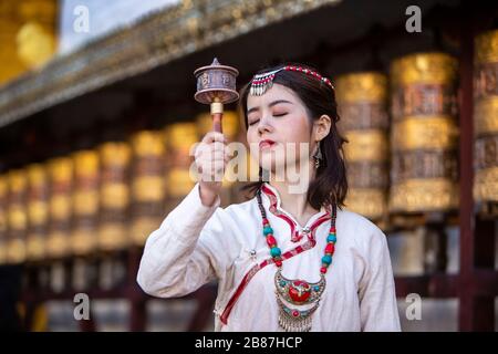 Roue de prière en rotation de la fille tibétaine à Barkhor, Lhasa, Tibet Banque D'Images