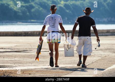 Deux pêcheurs sur le front de mer de la Havane transportant un poisson de basse mer. Image du peuple cubain. Banque D'Images