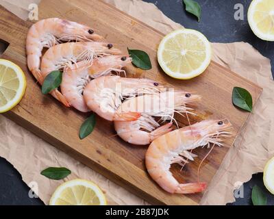 Cuisine, amour pour le concept de fruits de mer. De grandes crevettes tigrées au citron et au basilic sur un plan d'examen en bois comme arrière-plan. Studio photo, mise au point sélective Banque D'Images