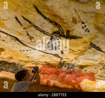 Un jeune visiteur voit une réplique d'une peinture préhistorique de caverne au Centre Lascaux de Montignac, en France. La réplique est d'un taureau dans la Chambre des taureaux. Banque D'Images