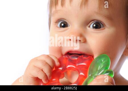 Un petit bébé d'un an tient à portée de main un jouet coloré de dentition. Jouet de dents d'enfant. Portrait sur fond blanc isolé Banque D'Images