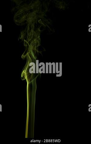 Fumée jaune abstraite tourbillonnant sur un fond noir. Banque D'Images
