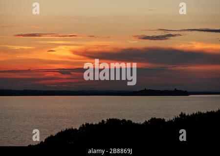 Coucher de soleil sur le lac Trasimeno en Ombrie avec Castiglione del Lago en arrière-plan Banque D'Images