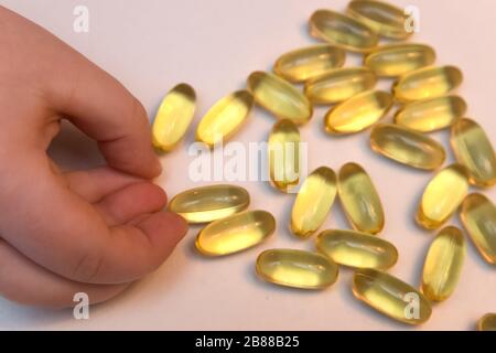 Vitaminen Omega 3 huile de poisson dans les capsules en main sur fond beige. Banque D'Images