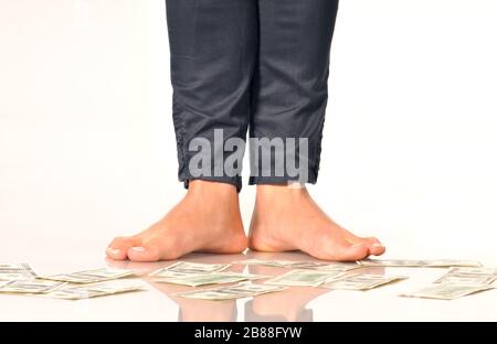 Les billets de banque en dollars au plancher sous les jambes des femmes pour impliquer la chute ou la dévaluation des devises des billets en dollars. Isolé sur fond blanc Banque D'Images