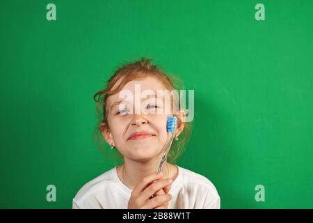 petite fille se brossant les dents sur un fond vert Banque D'Images