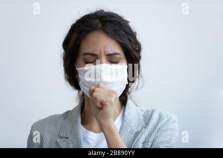 Une femme malsaine dans le masque toussant ayant des symptômes de maladie du coronavirus Banque D'Images