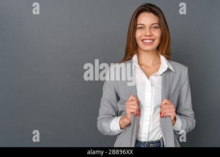 Jeune femme d'affaires studio isolé sur gris regarder caméra heureux Banque D'Images