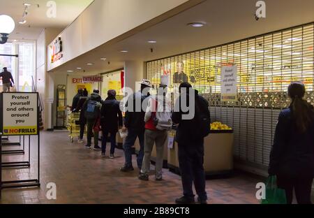 Vancouver, Canada - 20 mars 2020 : les gens s'unissent pour entrer dans le magasin sans frissons pratiquant l'éloignement social entre eux en raison de COVID-19. Banque D'Images