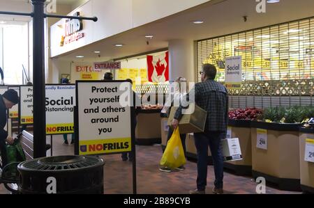 Vancouver, Canada - 20 mars 2020 : les gens s'unissent pour entrer dans le magasin sans frissons pratiquant l'éloignement social entre eux en raison de COVID-19. Banque D'Images