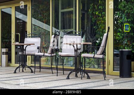 Tables et chaises sur la terrasse d'été du jardin d'hiver de l'immeuble d'appartements Banque D'Images