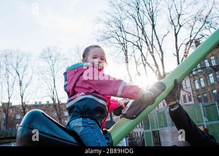 Jeune fille jouant dans un parc en Suède au coucher du soleil avec son père Banque D'Images