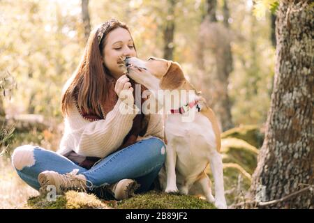 Jeune femme souriante, assise à côté de son chien pendant une promenade Banque D'Images