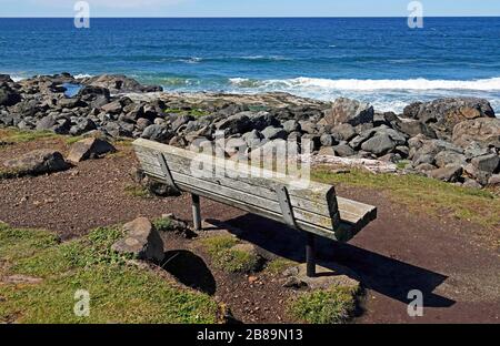 Un banc en bois isolé sur un point rocheux surplombant l'océan Pacifique sur un sentier en bord de mer dans le petit village de Yachats, Oregon. Banque D'Images