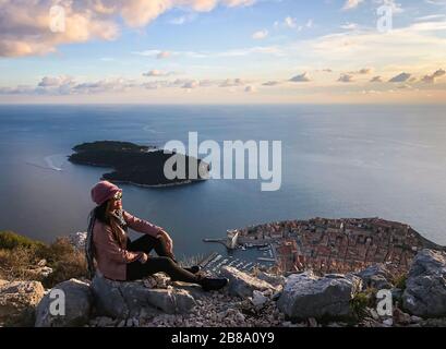 Une femme souriante et heureuse, qui bénéficie d'une vue sur la vieille ville de Dubrovnik depuis le dessus au coucher du soleil, la mer Adriatique de Croatie Banque D'Images