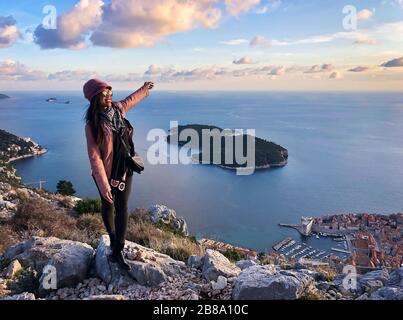 Une femme souriante et heureuse, qui bénéficie d'une vue sur la vieille ville de Dubrovnik depuis le dessus au coucher du soleil, la mer Adriatique de Croatie Banque D'Images