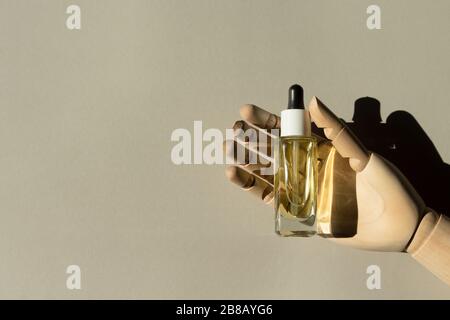 Les mains en bois contiennent une bouteille d'huile organique naturelle à base de sérum de collagène. Concept créatif de soins spa. Composition minimaliste avec ombre. Banque D'Images