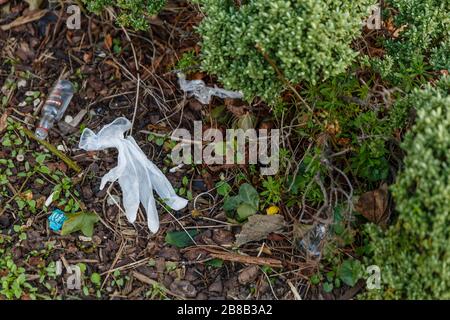 Middlesex, Royaume-Uni. 21 mars 2020. Un gant en caoutchouc jeté et une bouteille de vodka miniature vide s'assoient entre autres dans un parc local. Les gens portent des gants en caoutchouc pour se protéger du coronavirus COVID-19. À mesure que la pandémie se répand, l'assainisseur pour les mains, ainsi que d'autres produits essentiels, tels que le papier toilette et les aliments non périssables, ont été vendus dans les supermarchés pendant des semaines. Les gens ont cherché des solutions de lavage à la main et comme l'alcool isopropylique est maintenant épuisé, les médias sociaux ont suggéré la vodka comme un substitut. Crédit: amanda rose/Alay Live News Banque D'Images