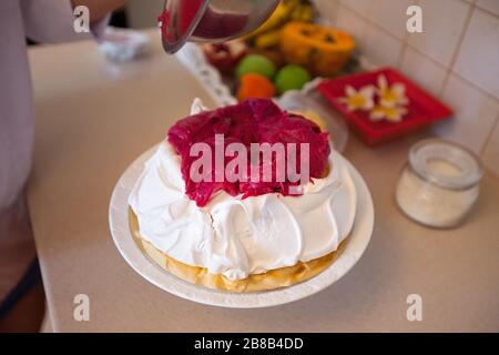 Faire du gâteau Pavlova avec de la crème aux fruits Banque D'Images
