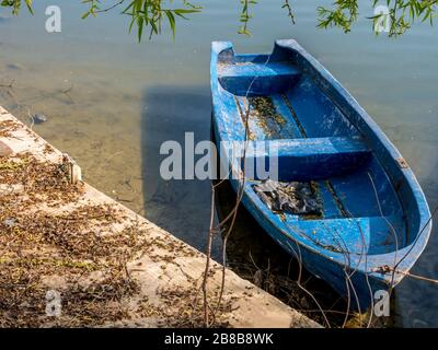 Vieux bateau de pêche bleu. Un bateau en bois usé sur un lac. Banque D'Images