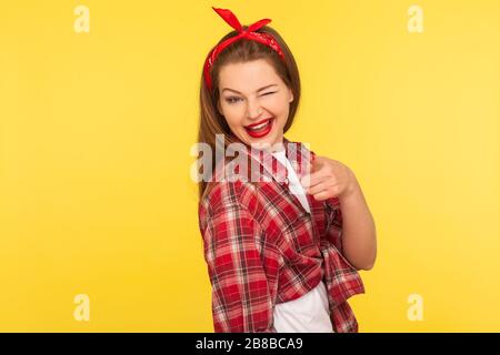 Hé toi ! Portrait d'une jeune fille en coquette joyeuse dans une chemise à carreaux et un bandeau encrant avec un look espiègle et pointant vers l'appareil photo, en choisissant winn Banque D'Images