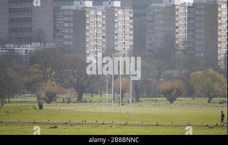 Richmond Park, Londres, Royaume-Uni. 21 mars 2020. Les parcs royaux sont ouverts aux cyclistes et aux piétons, mais avec des cafés intérieurs fermés pendant la crise de Coronavirus. Un jogger court au premier plan dans un contexte de la propriété Alton, l'un des plus grands sites de conseil des UKs. Crédit : Malcolm Park/Alay Live News. Banque D'Images