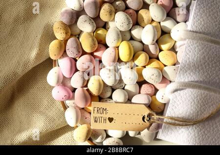 Plusieurs oeufs de Pâques colorés au chocolat sur la plaque ronde, sac cadeau en toile, bouquet de fleurs bleu printemps. Mise à plat, vue de dessus. Pâques, symbole du printemps Banque D'Images