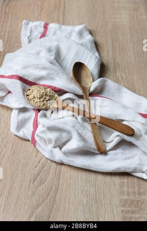 Poudre de racine de Maca dans une cuillère en bois, super nourriture, sur un tissu blanc Banque D'Images