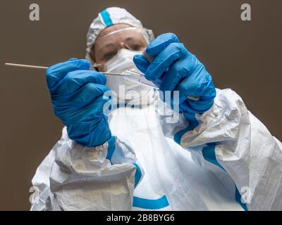 Une femme, un technicien de laboratoire, recouverte d'une couverture blanche protectrice, fait un écouvillon de test pour vérifier la présence éventuelle d'une contagion du Coronavirus Covid-19 Banque D'Images
