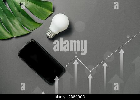 Créativité inspiration, idées concepts avec ampoule, diagramme numérique, interfaces graphiques, montera de feuilles vertes et smartphone moderne avec espace de copie o Banque D'Images